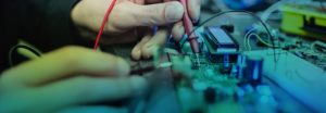 Hands testing circuit board with multimeter